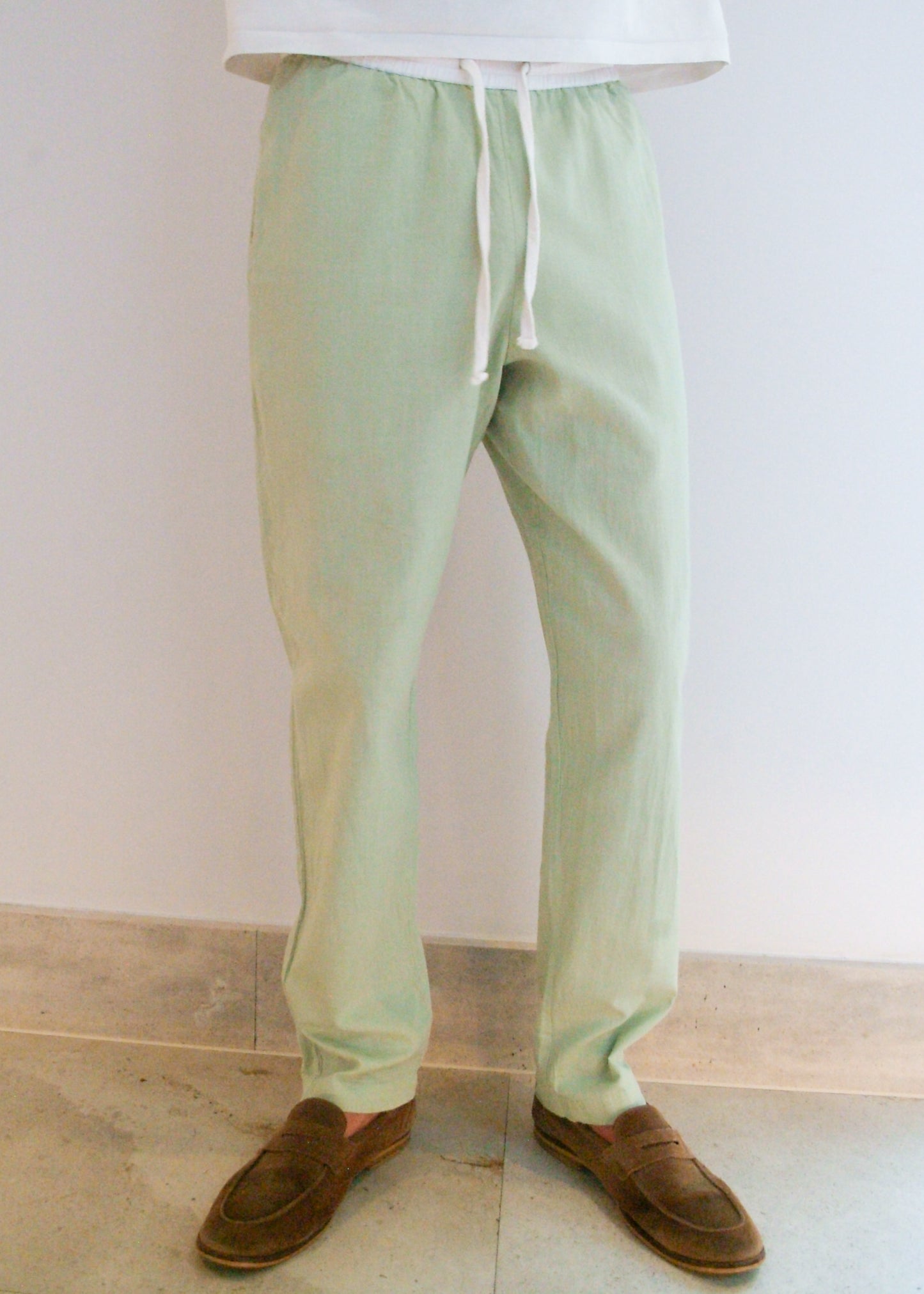 Light green capts daughter pants worn by a person on a plain background