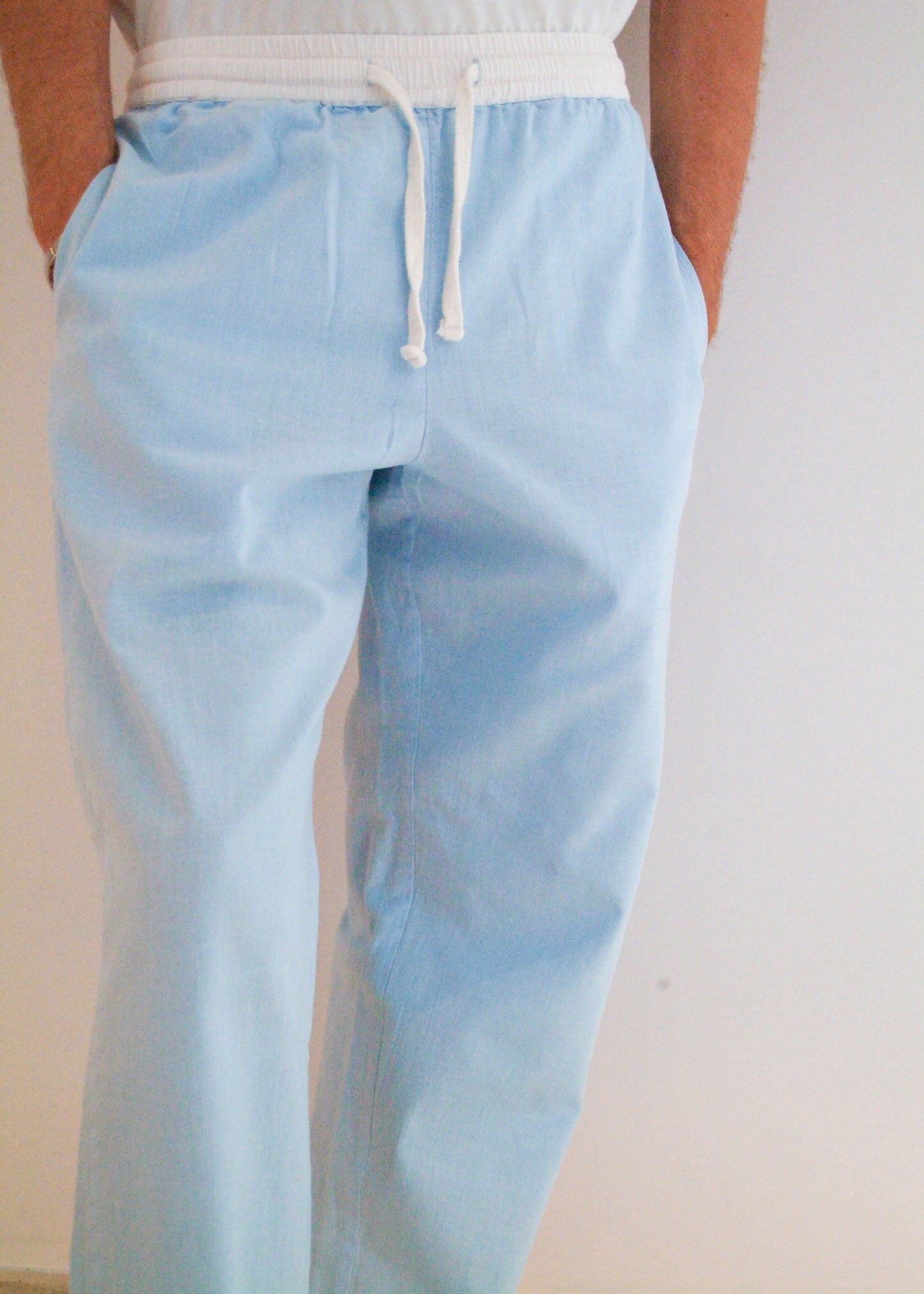 Light blue pants with a white top worn by a person against a plain background