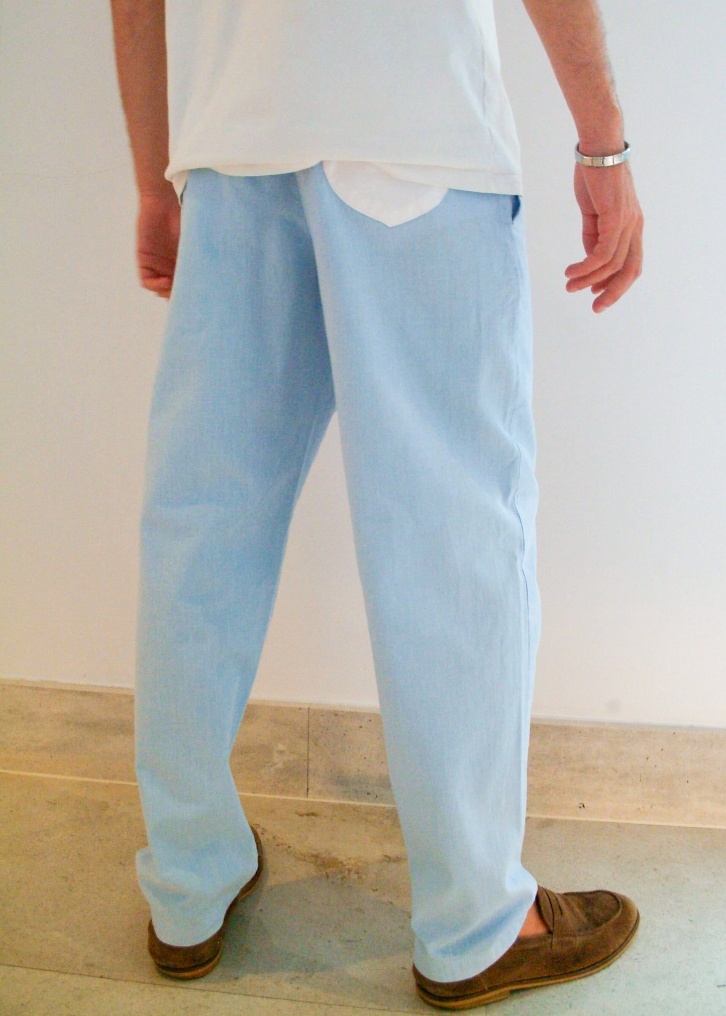 Person wearing light blue jeans and brown shoes on a plain background