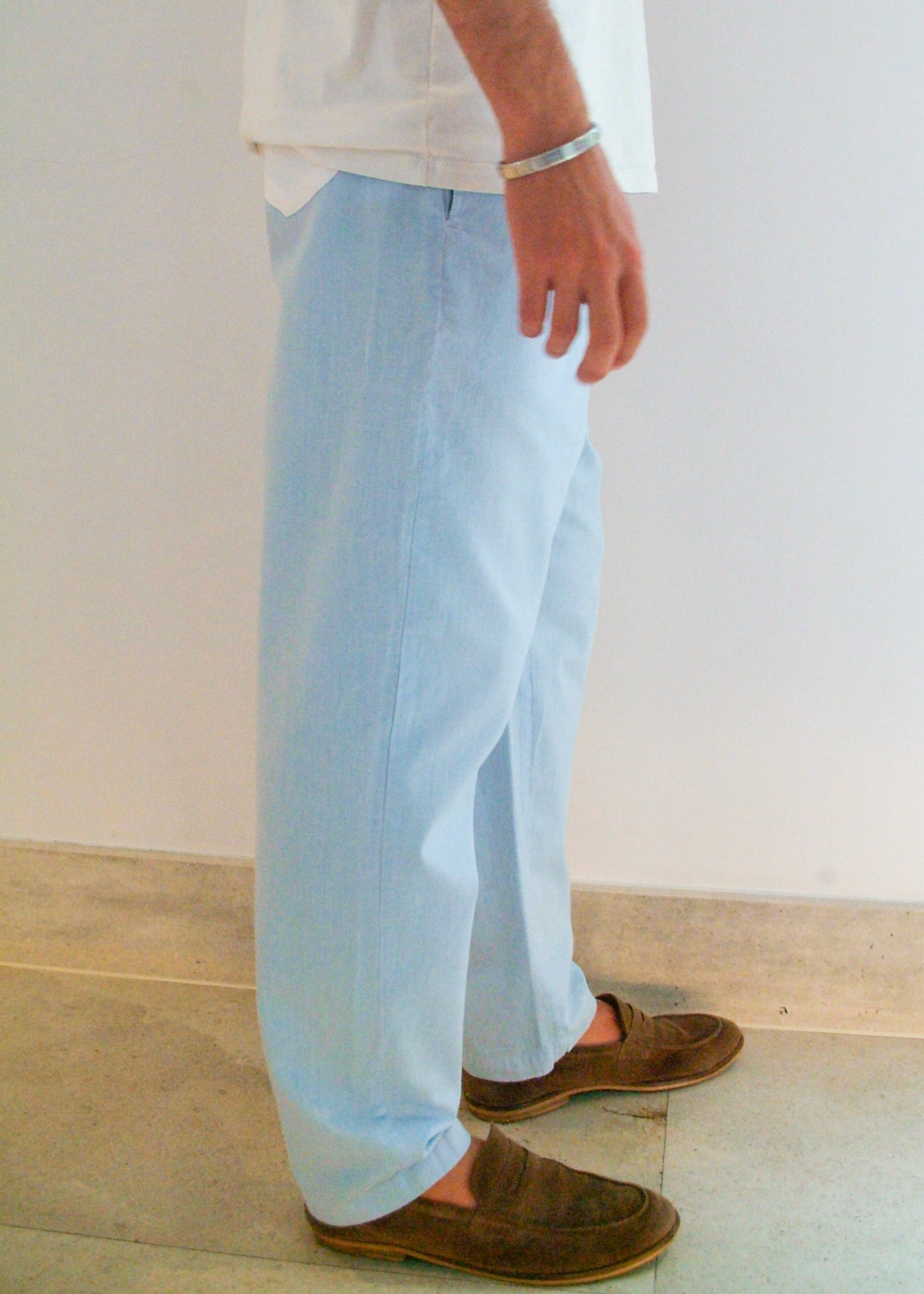 Person wearing light blue pants and brown shoes on a plain background