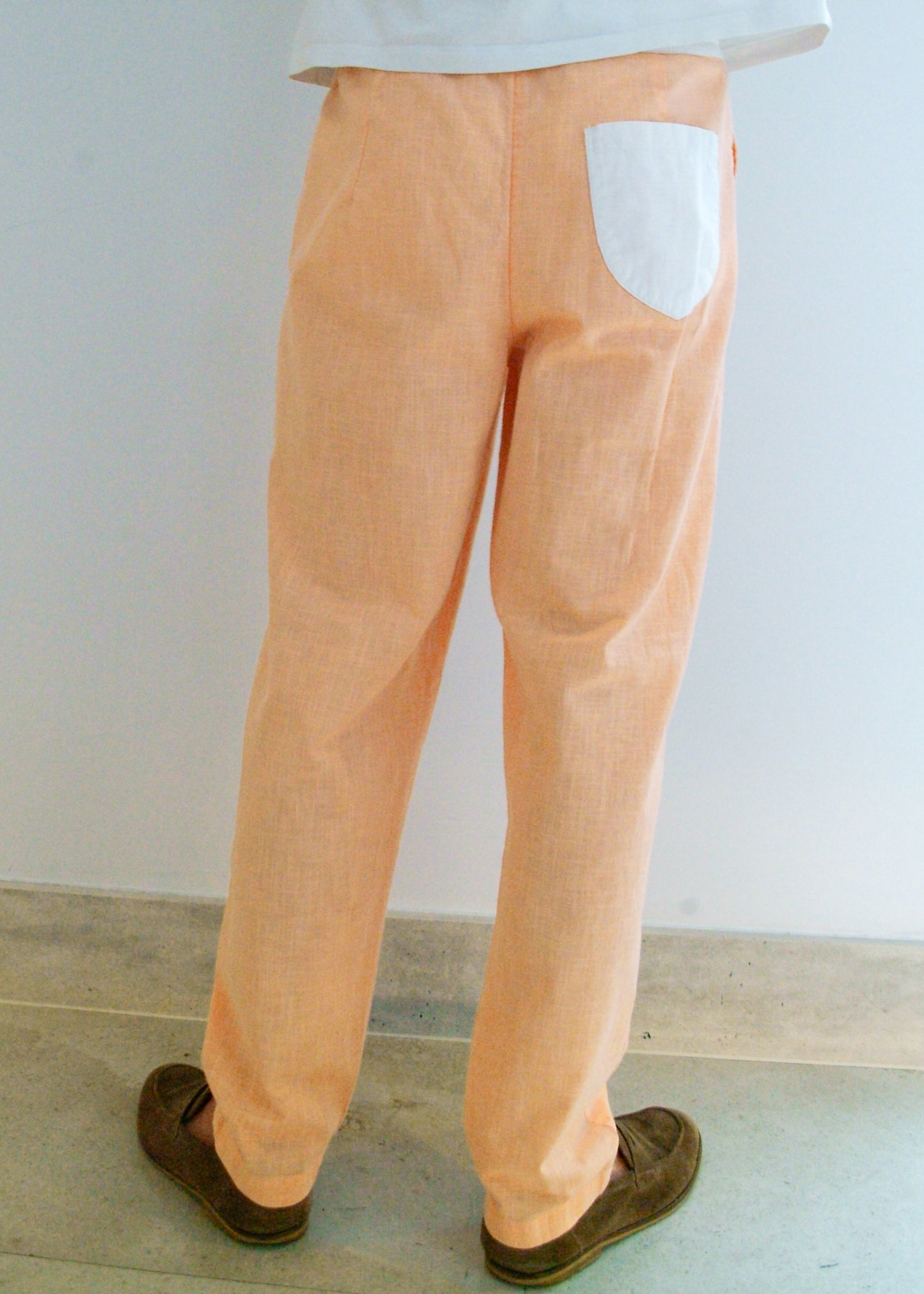 Person wearing peach-colored pants with a white wall background