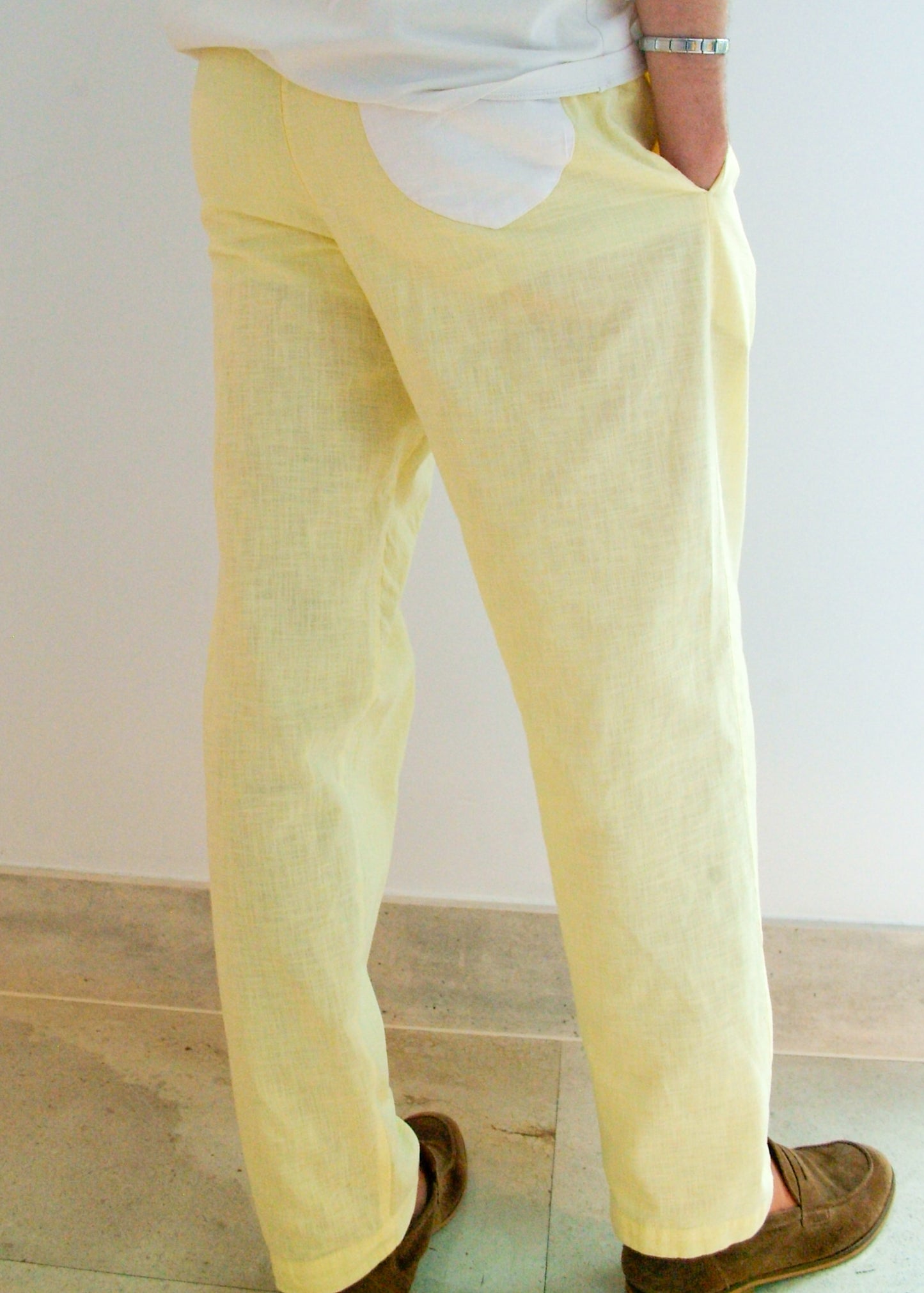 Person wearing light yellow pants and brown shoes on a plain background