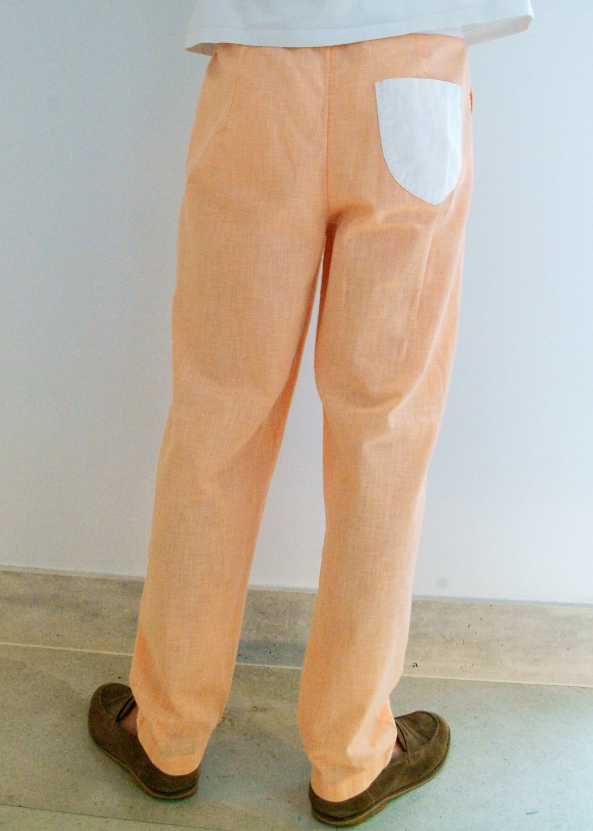 Person wearing peach-colored pants with a white wall background