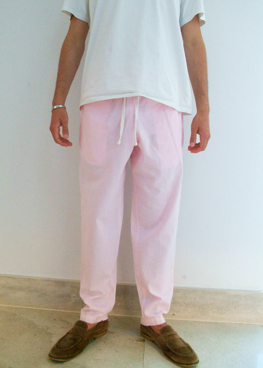 Person wearing light pink pants and a white shirt against a plain background